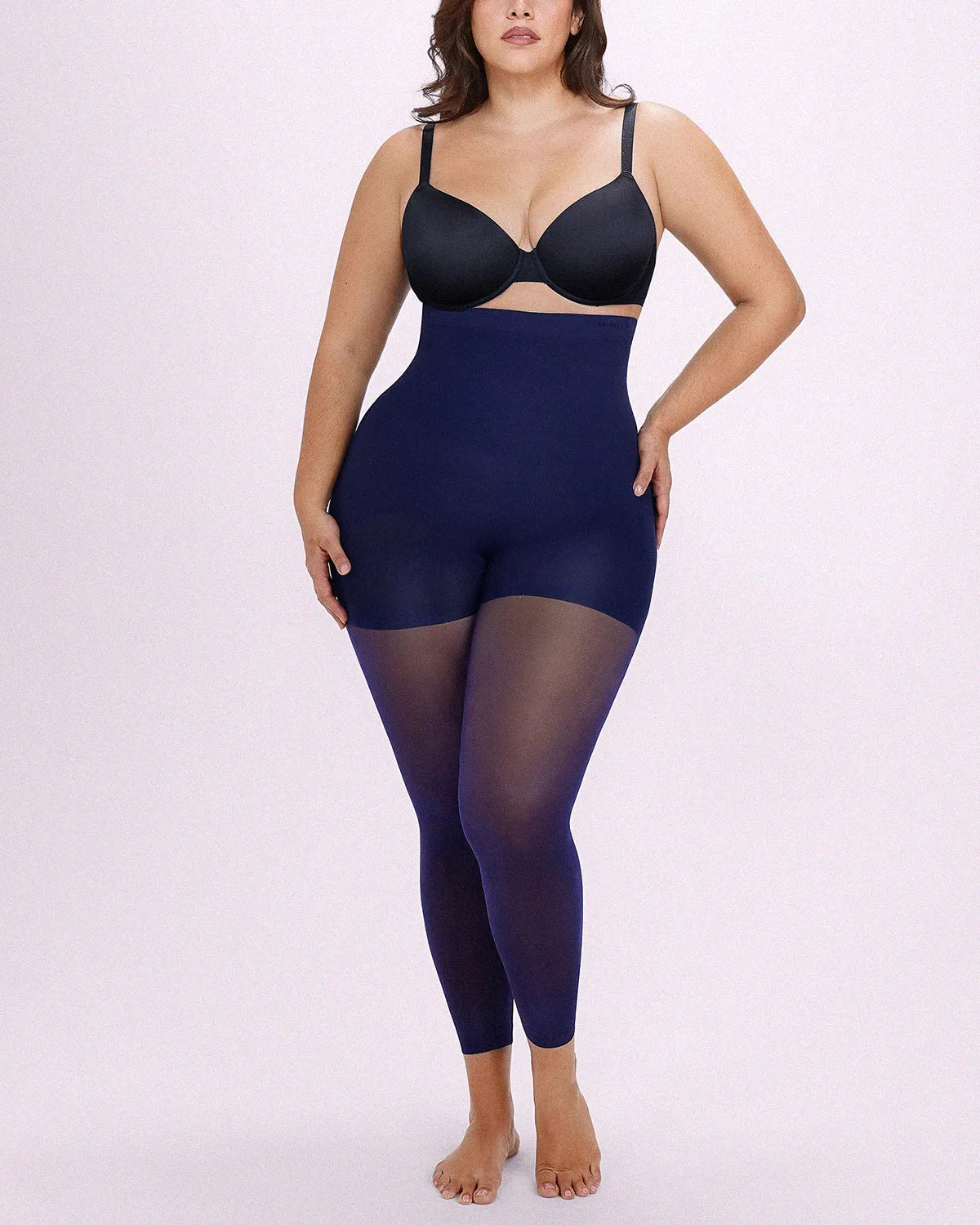 Model facing front in navy blue shaping tights engineered with targeted midsection flattening and all-day breathable comfort
