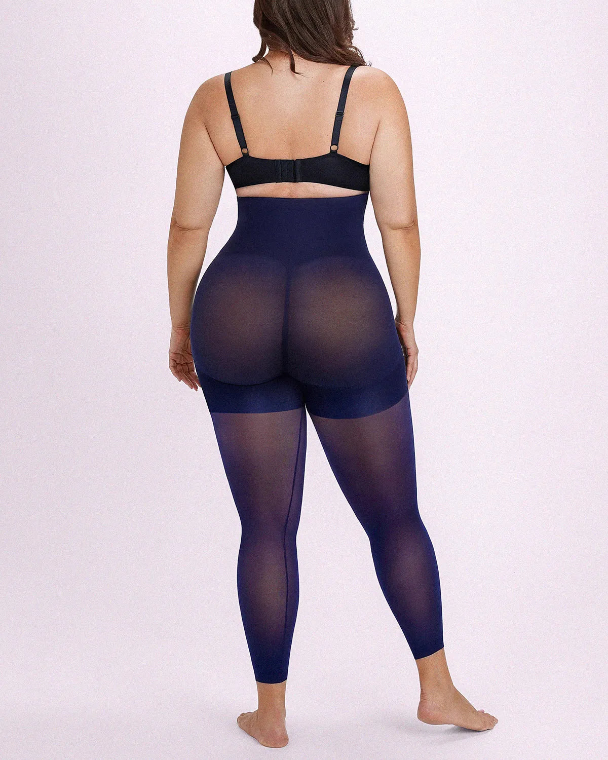 Rear-angle view displaying navy blue all-in-one shaping tights with seamless one-piece knitting and natural rear support
