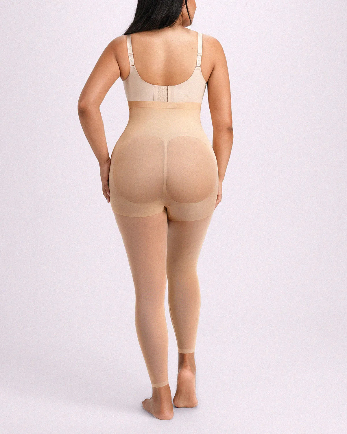 Rear-angle view displaying beige all-in-one shaping tights with seamless one-piece knitting and natural rear support